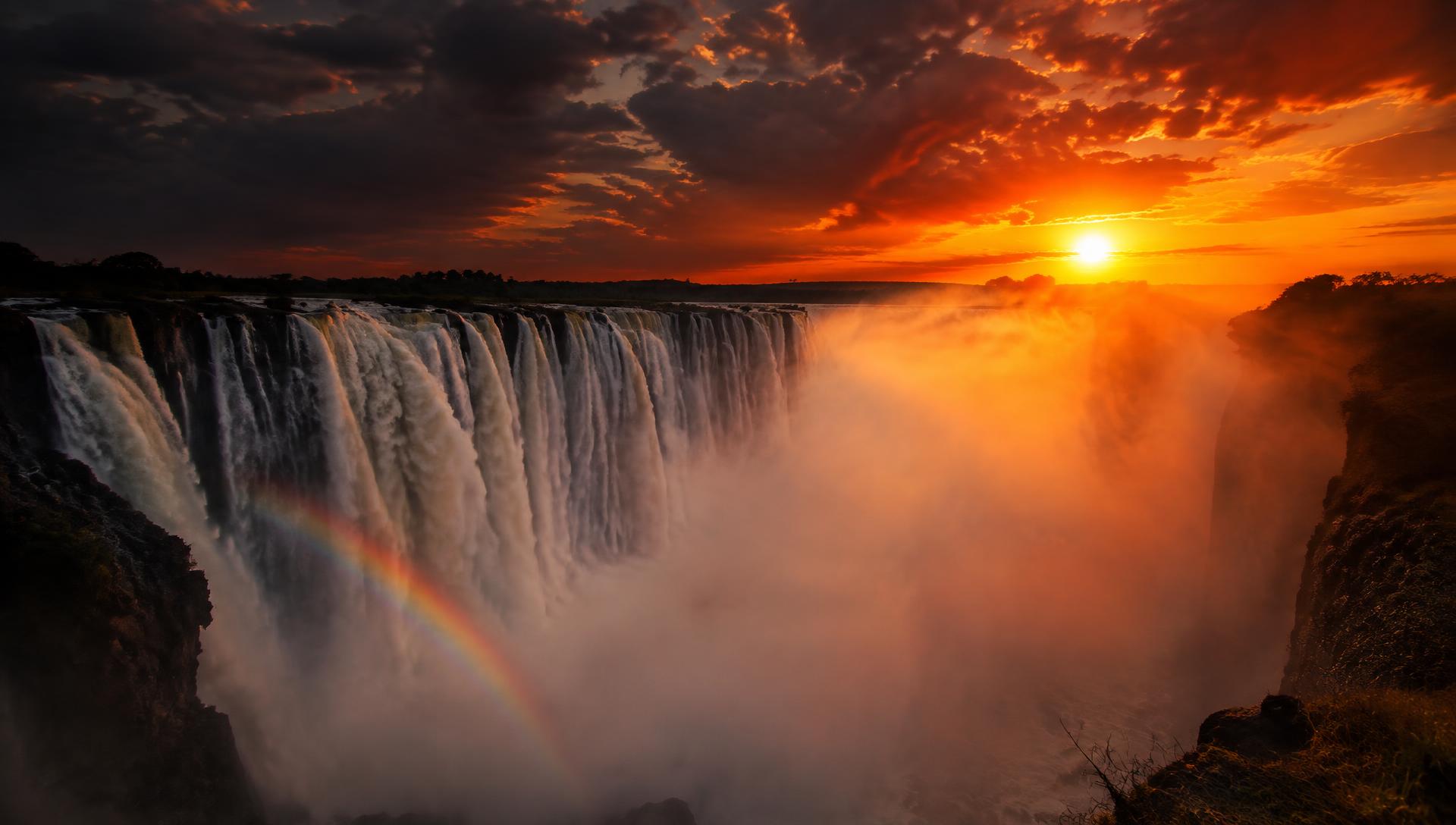 Victoria Falls at sunset, mist rising with a rainbow